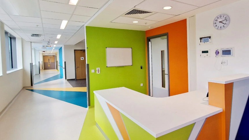 The inside of a hospital building, with bright colours on the walls and floors and welcome desk