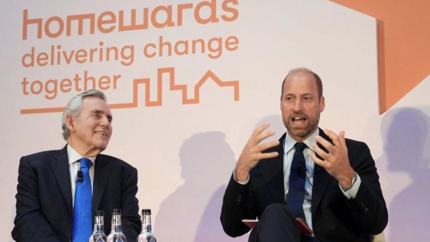 The Prince of Wales (right) and former Prime Minister and Multibank Founder Rt Hon Gordon Brown Left) on white chairs. Gordon Brown is laughing while Prince William speaks and gesticulates.
