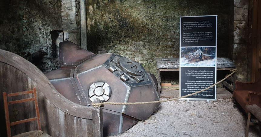 A prop of a space ship sits on display next to a board describing what it is
