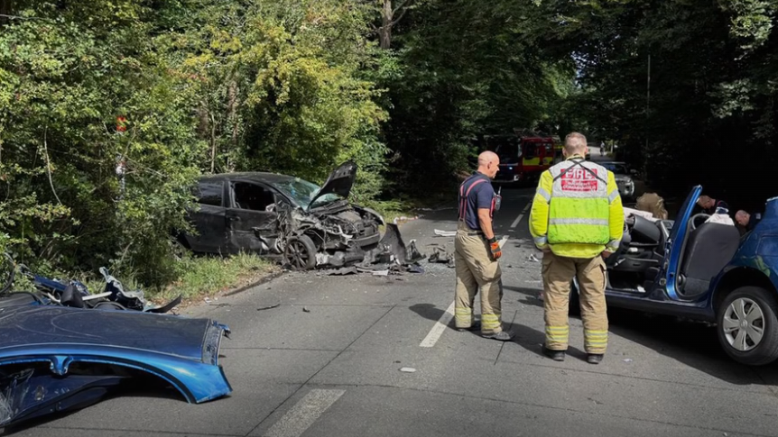 Site of a car accident with two people standing over a car
