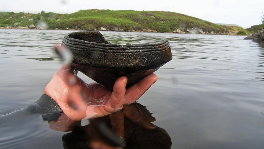 Diver's hand holding Neolithic pottery