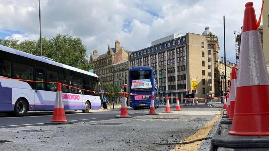 The newly-laid road surface buckling at the kerbside due to flooding