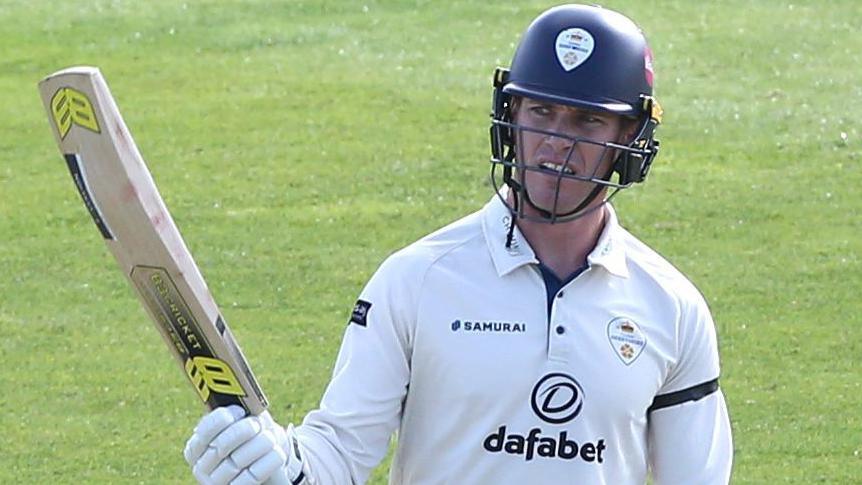 Luis Reece raises his bat after reaching a half-century for Derbyshire