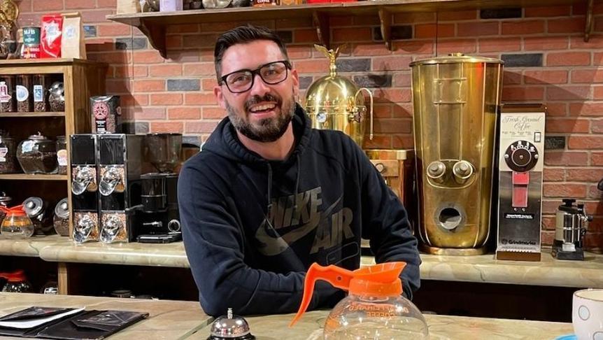 Jordan Hayes sits behind the coffee counter on the set of a Friends pop up in Dallas. He says he's a foodie who can taste the difference when Coke is made with sugar