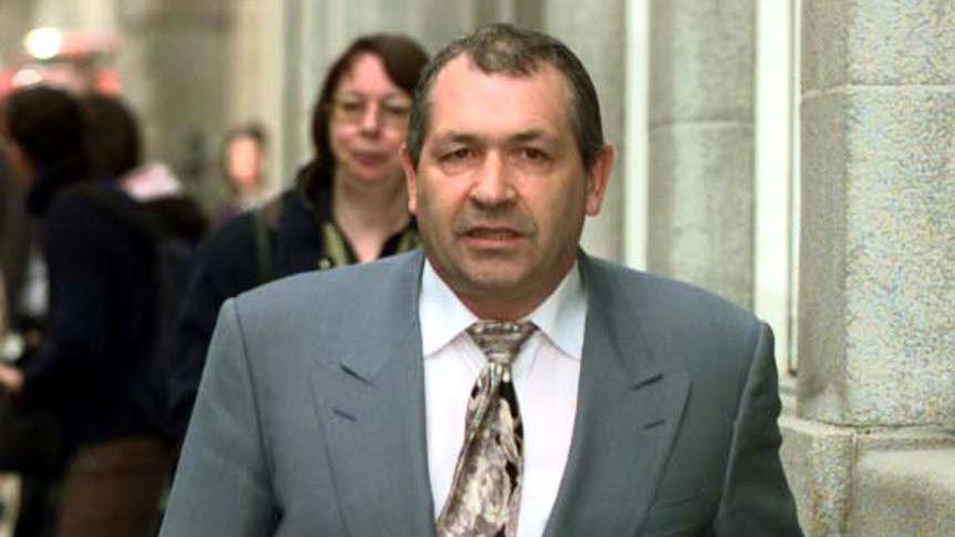 John Palmer in a grey suit, white shirt and tie walking towards the camera outside the Old Bailey in 2001.