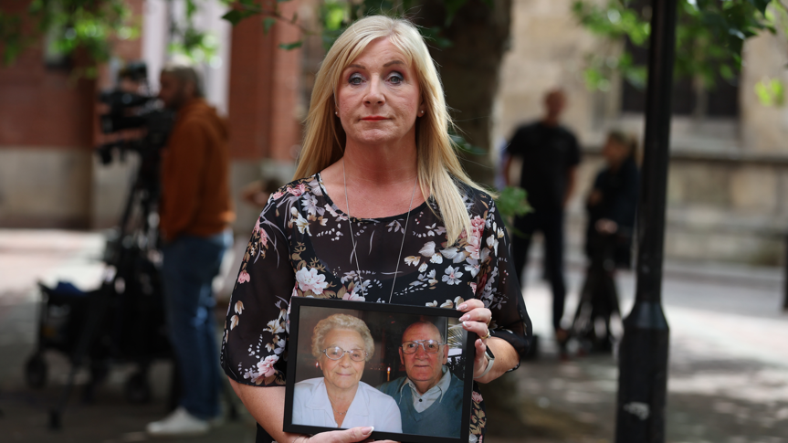 Karen Dry, holding a photograph  of her parents, extracurricular  Hull Crown Court. She has agelong  blonde hairsbreadth  and is wearing a achromatic  floral dress.