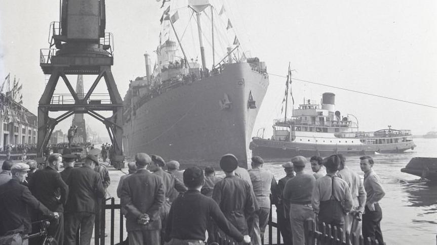 Archive image of a ship coming into docks in Southampton with dock workers looking on