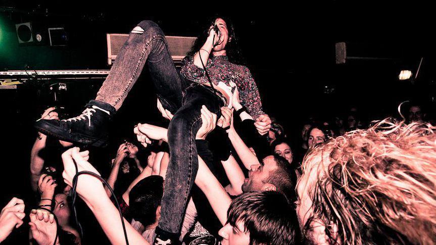 A singer is being carried aloft by the audience at a gig at The Croft.