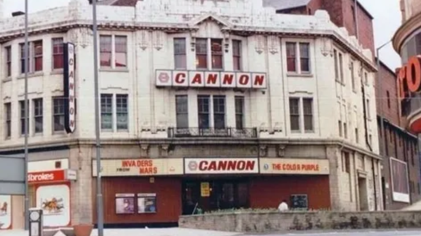 A large old white stone building with a large red sign with the letters CANNON on the front