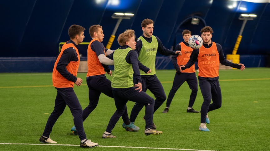 A group of six AC Oulu players, including Englishman Ashley Coffey and Northern Irishman Jake Dunwoody, train indoors inside an astroturf dome