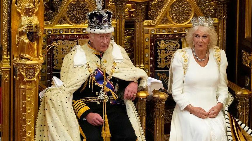 King Charles and Queen Camilla in ceremonial clothes including crowns in the House of Commons   