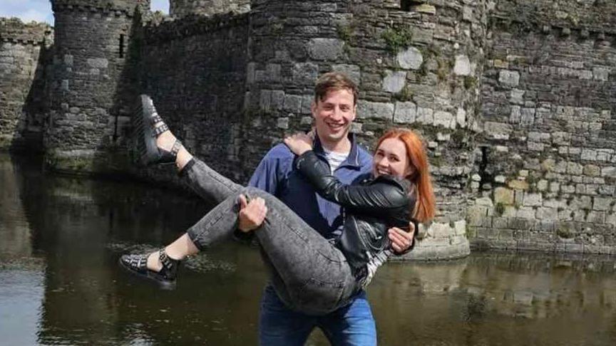 Kyle is seen lifting his girlfriend Sasha up in the air outside a castle.