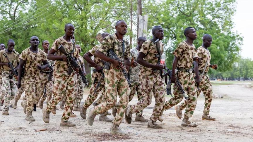 Nigerian soldiers dressed in uniform train while holding guns