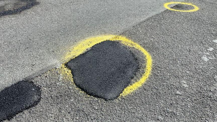 A filled in pothole with yellow spray paint around it.