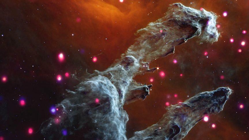 Backed by dark orange mist, the cloudy gray columns are surrounded by dozens of soft, glowing, pink and purple dots.
