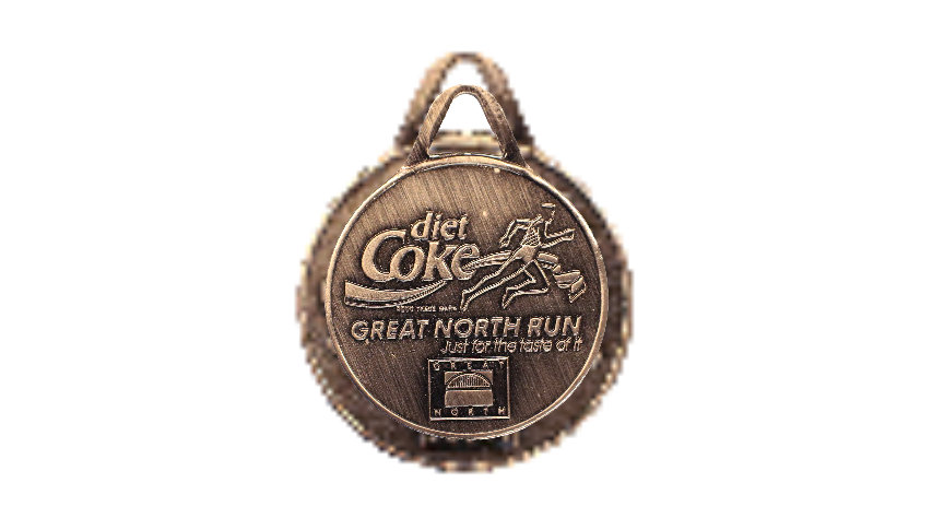 A circular bronze and silver coloured medal, that reads 'diet coke' and has a runner crossing a ribbon. Underneath it reads 'great north run, just for the taste of it'. 