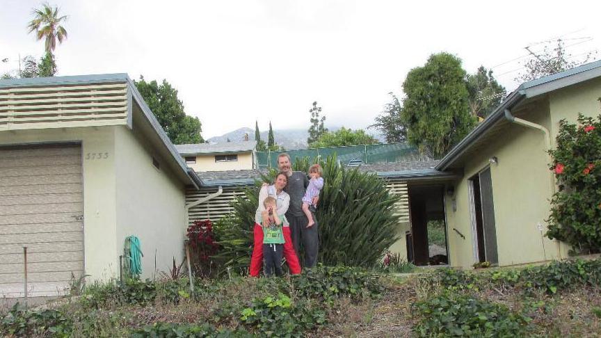 A couple standing in the front garden holding two young children