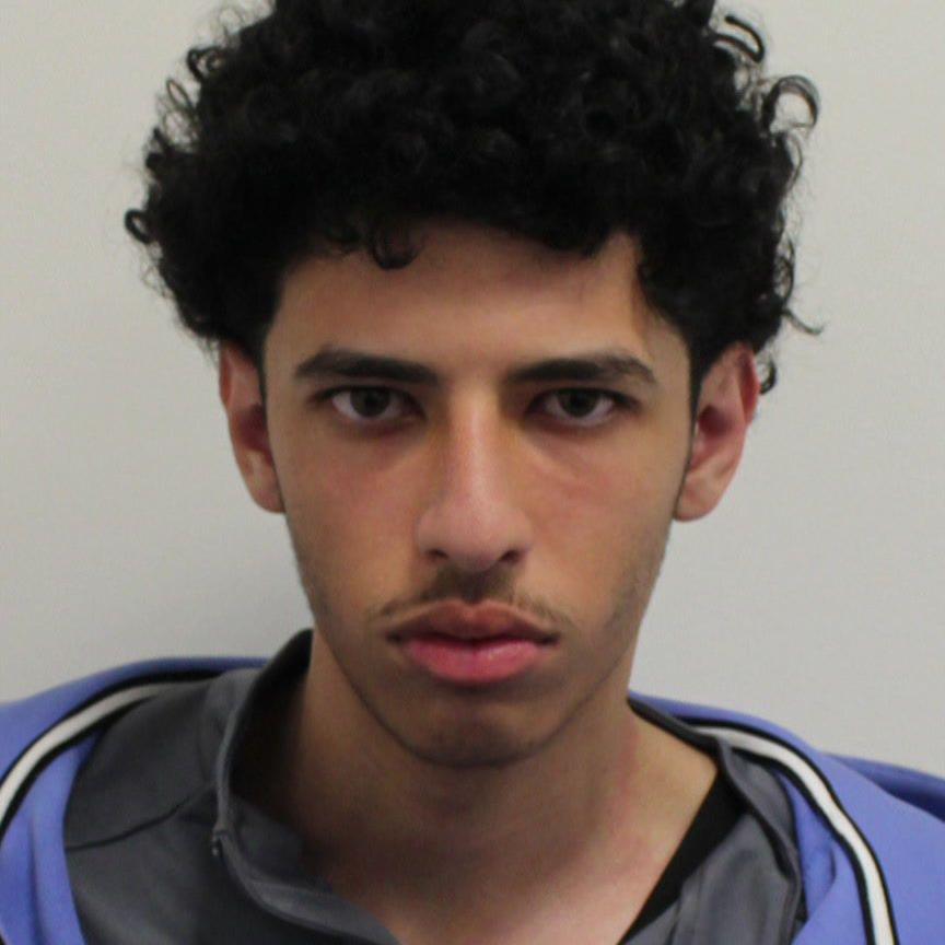 Nabil Mezali in a police custody photo, he appears to be wearing a blue tracksuit with a black top underneath 