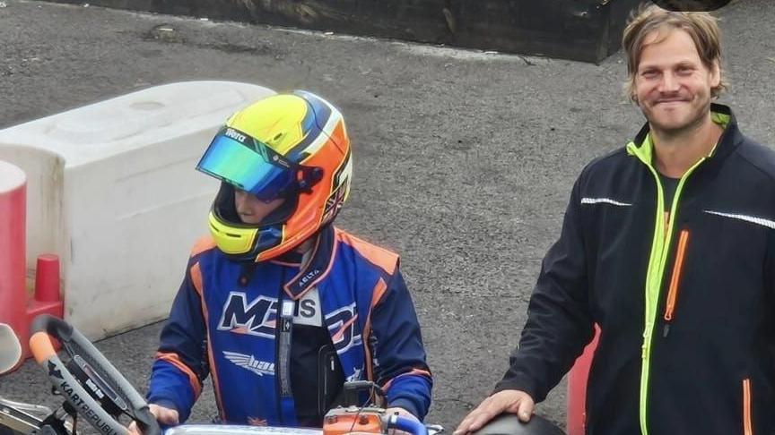 Matthias is on the left wearing a black jacket and his son Jacob is on the right, wearing a biker's helmet and a blue racing jacket