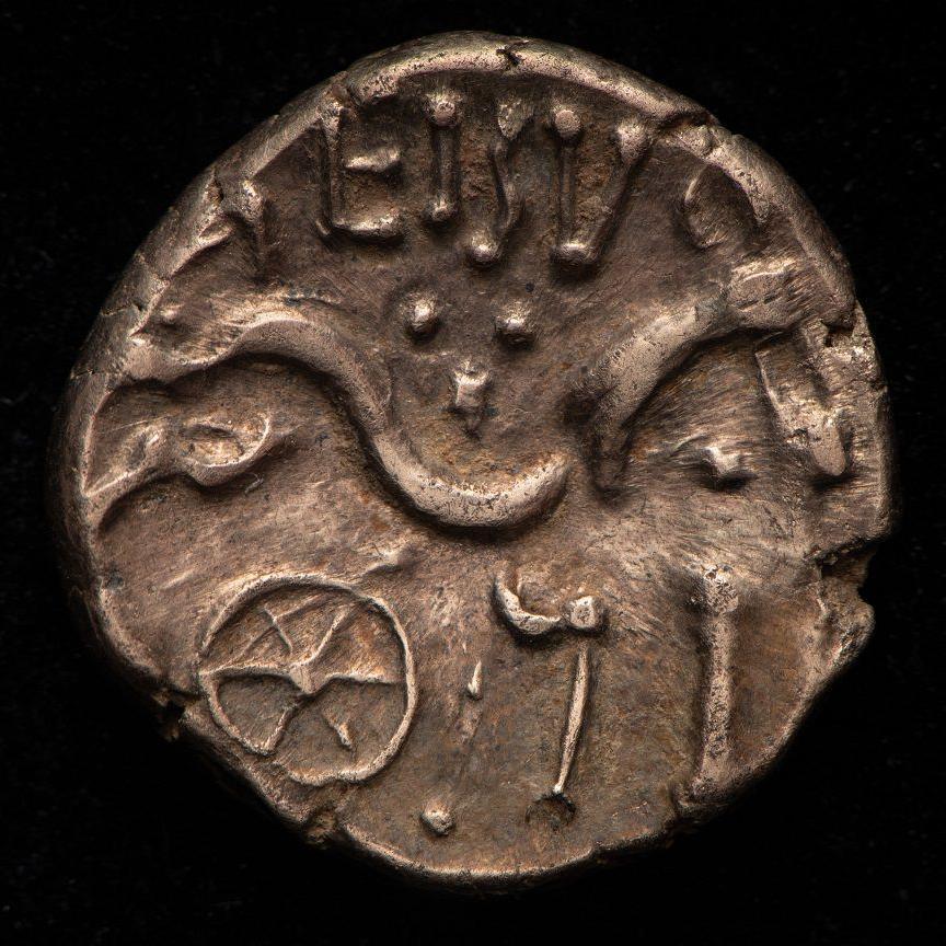 A Roman silver coin with a press of a wheel and curved images