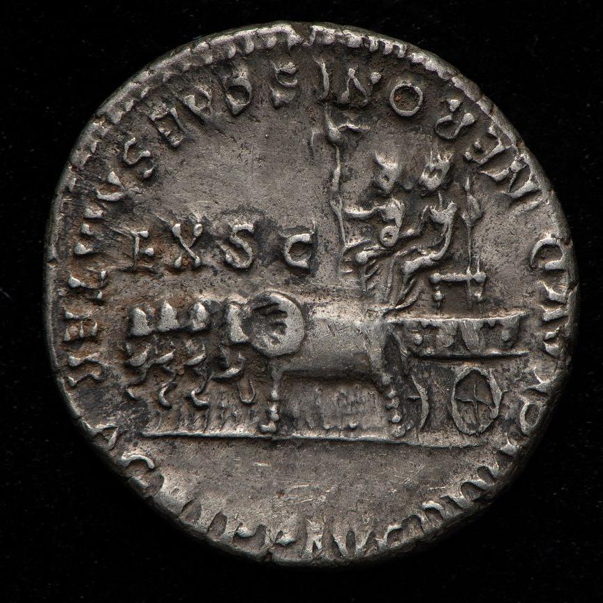 A Roman silver coin with a press of two people on a chariot being pulled by a number of animals