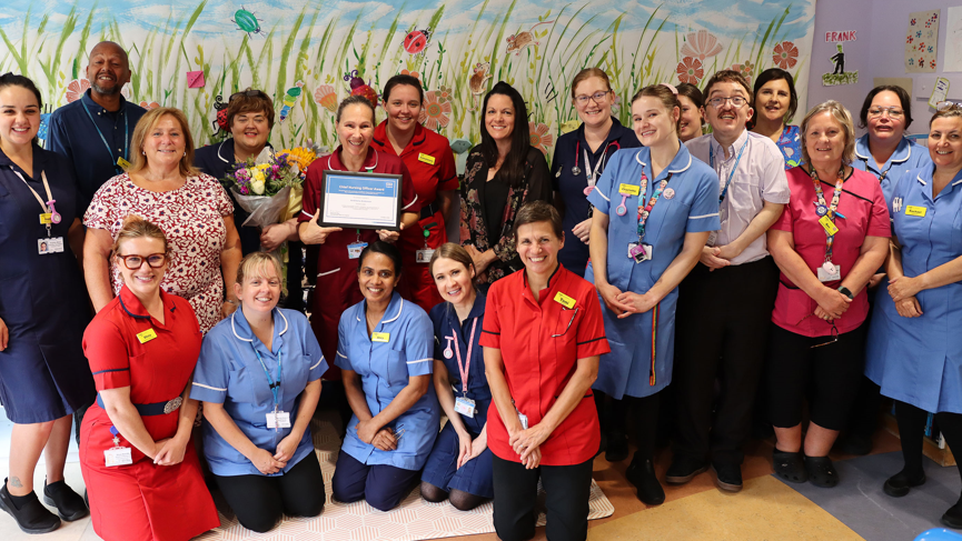 A team of RUH healthcare workers gathered round Andreena Anderson, who is holding her framed award