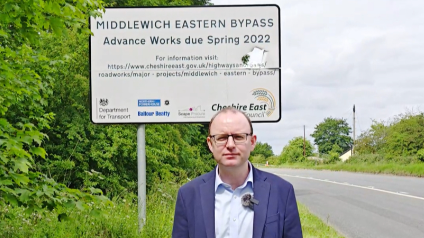 Mid Cheshire MP Andrew Cooper standing in front of a sign about works for the Middlewich Eastern Bypass. It says advance works due to start Spring 2022.