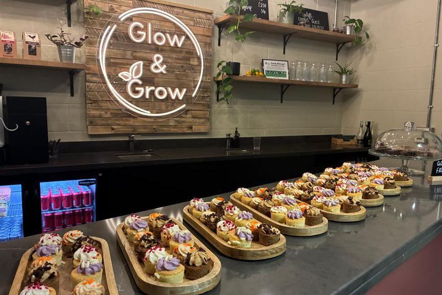 Trays of canapes on a shop counter. There is a sign above a fridge of Coca Cola Coke Zeroes which reads: GLOW & GROW.