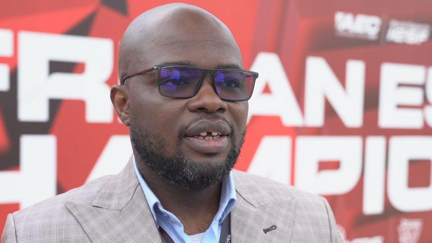 Emmanuel Oyelakin the secretary general of the African Confederation of Digital Sports, is pictured wearing a grey suit jacket and a blue shirt