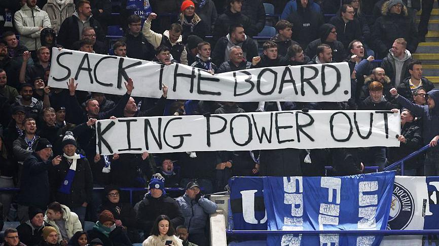 Leicester City fans hold a banner in protest to the club's board
