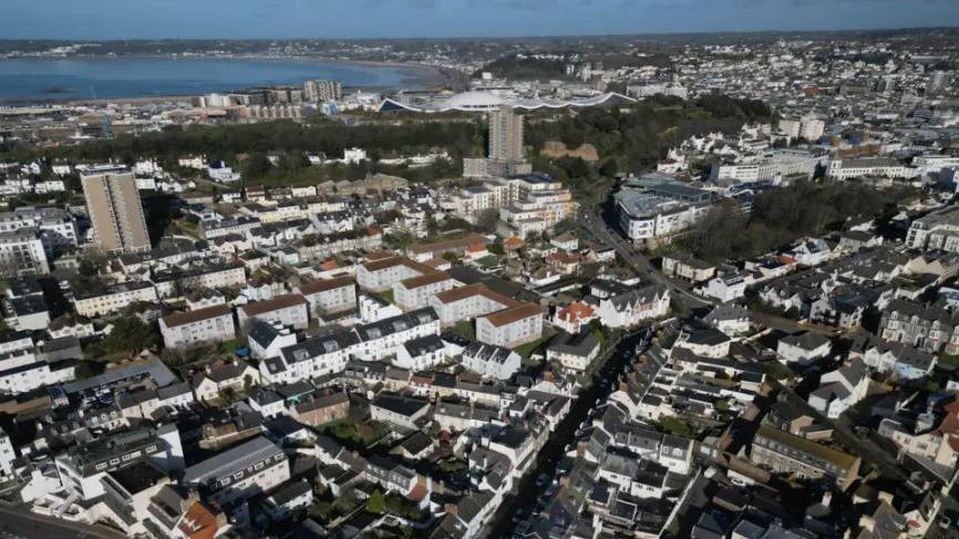 An aerial view of Jersey showing houses, green space and the sea.