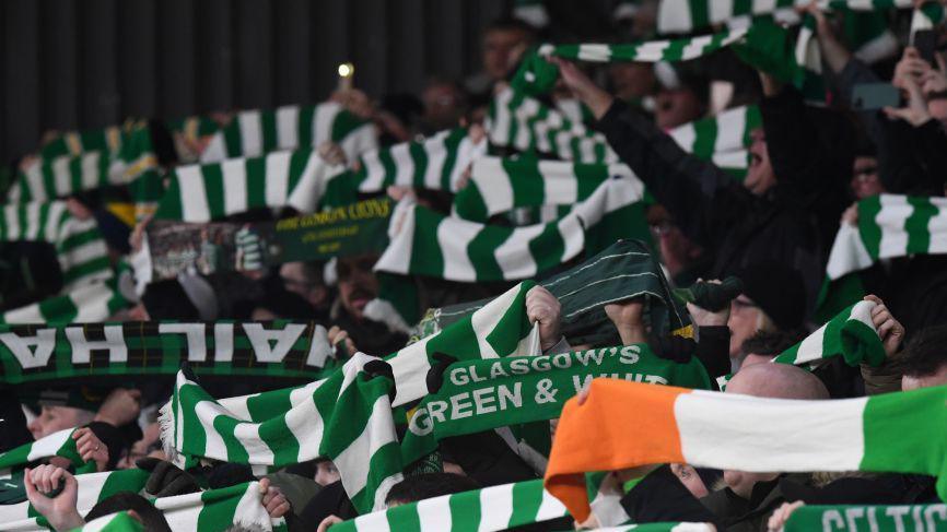 Crowd of Celtic FC fans holding scarves, with green and white stripes.