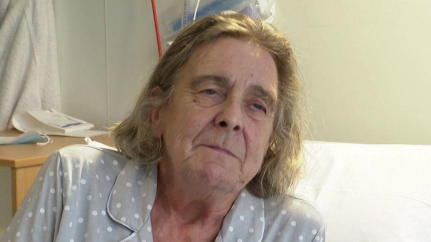 Sheila Tonks in her hospital bed wearing grey and white spotty pyjamas, she has grey short hair.