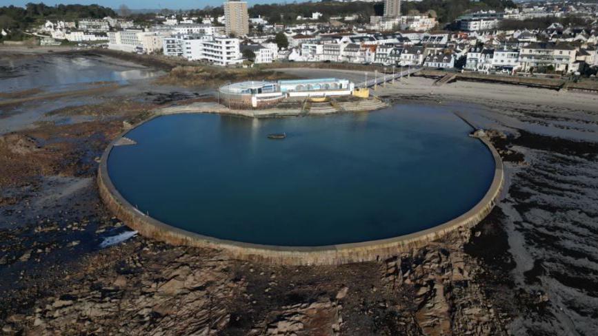 A general view of the lido. There is a large body of water with houses and buildings in the distance.