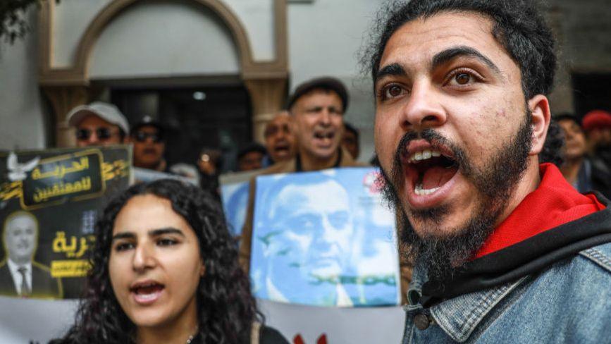 Protesters shout and wave banners outside the court on Tuesday.
