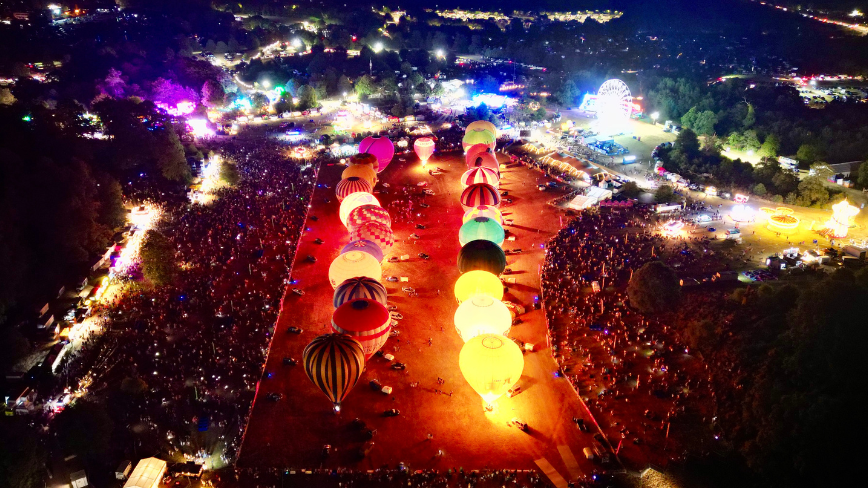 A view over the balloon fiesta with balloons being lit up.