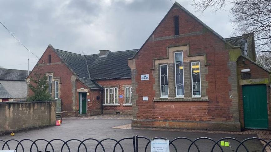 Old School Hall in Barlestone made of red brick with a gated fence 