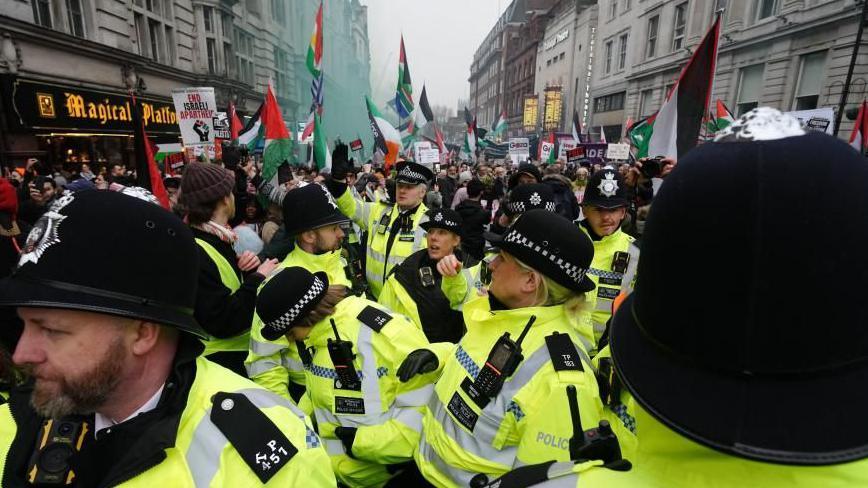 Police officers watch as people take part in a pro-Palestinian march  on Whitehall in central London