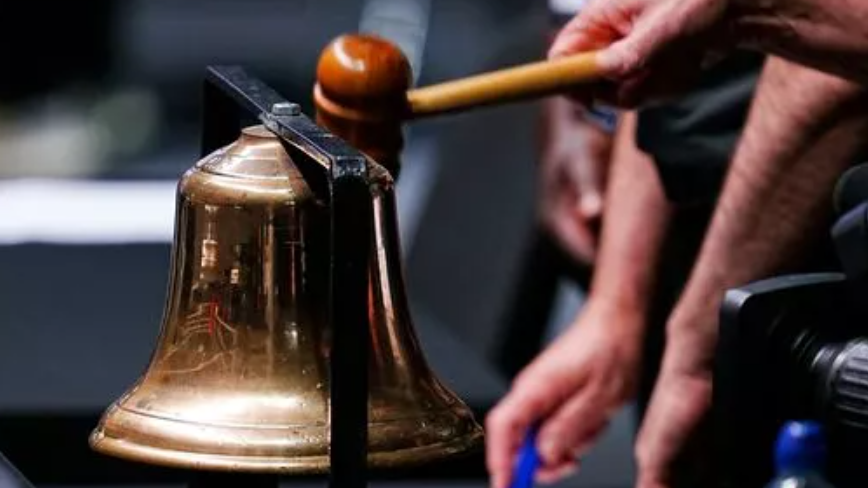 A close-up photo of an official banging a gold bell with a hammer at the world championships.