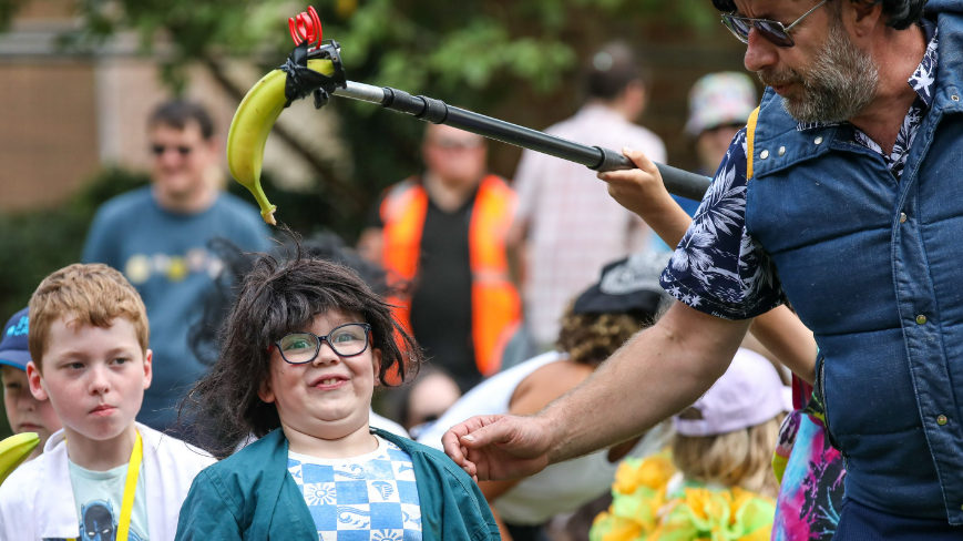 A child looks shocked as a banana "microphone" is held above his head.