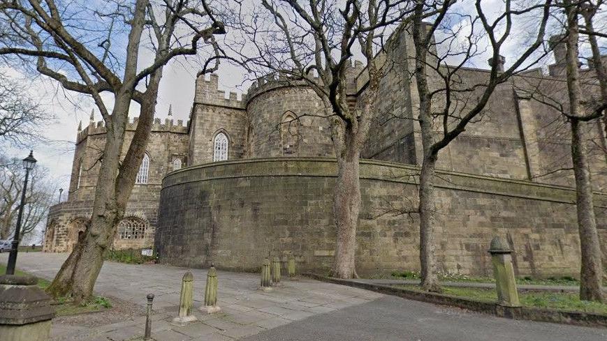 A stone building with arched mullioned windows, which is part of Lancaster Castle