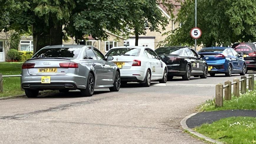 A row of taxis outside a Cambridgeshire school