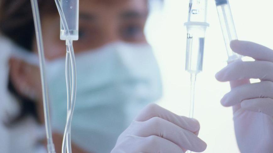 A medic in a mask holds a syringe