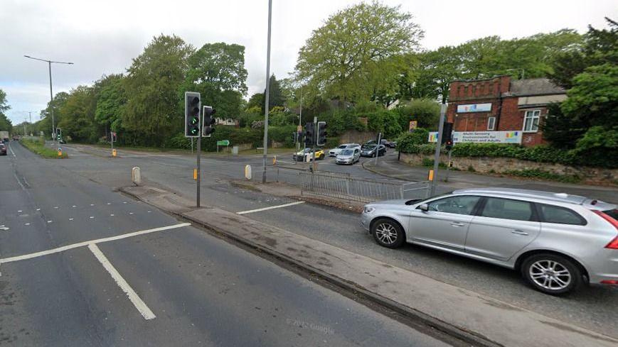 A silver car waits at the traffic lights at a junction