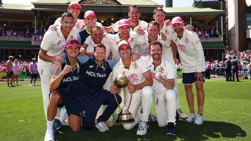 Australia team celebrate beating India with captain Pat Cummins holding the Border-Gavaskar trophy