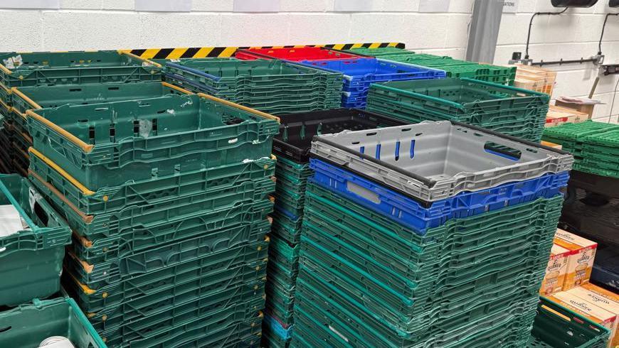 The photo shows towers of different coloured empty crates stacked on top of each other. Each stack contains 15 to 20 crates.
