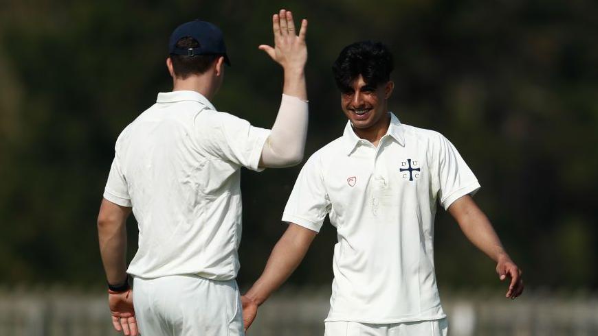 Nikhil Gorantla [right] goes to high five a team-mate while playing for Durham's second XI, with both players dressed in white cricket kits