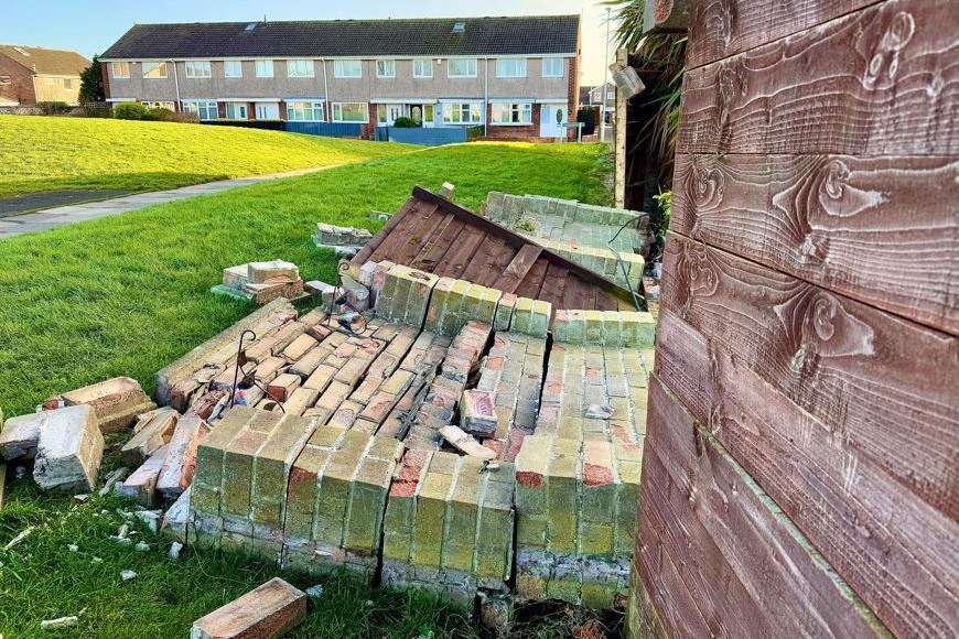 A waist-height brick wall has been blown over on a housing estate.