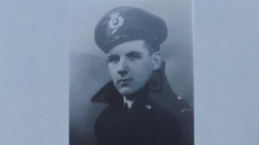 A black and white portrait photo of Russ Proudfoot looking serious in a uniform and cap
