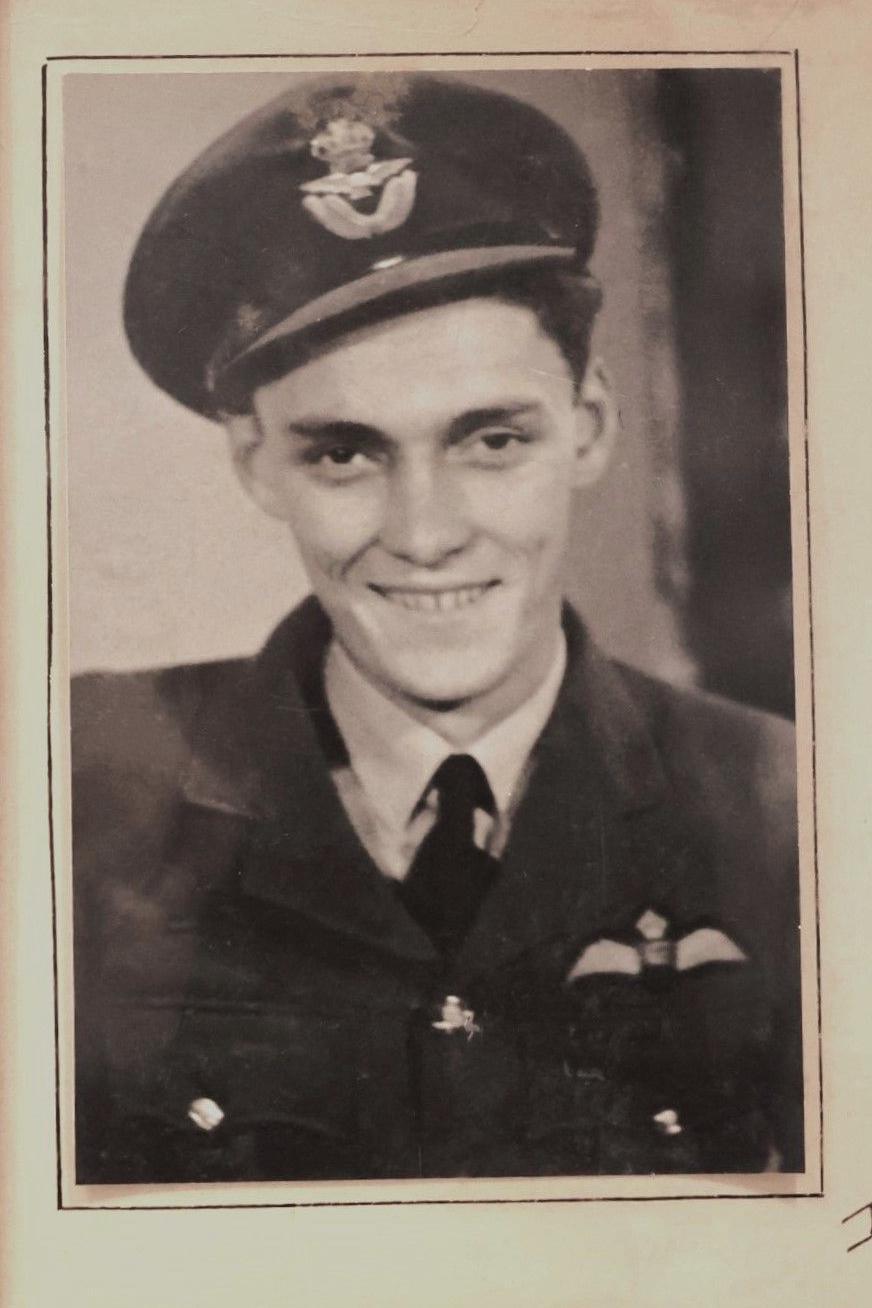 A black and white photograph of Pete Le Brocq in his RAF uniform smiling broadly at the camera. 